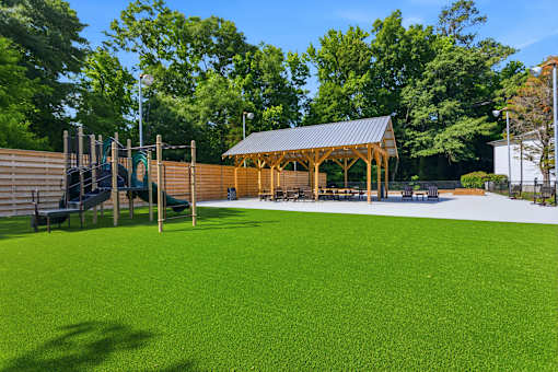 A playground with a green surface and a wooden pavilion.