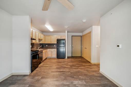 A kitchen with a black fridge and wooden cabinets.