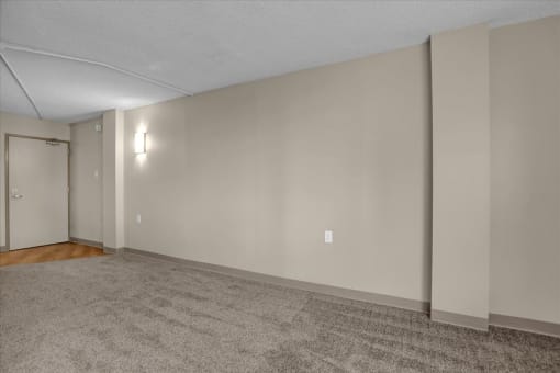 the living room is empty and has a door to the bedroom