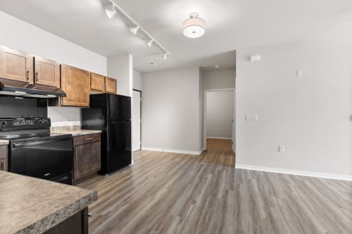 a River Flats kitchen with black appliances, wood-cabinets, and track lighting