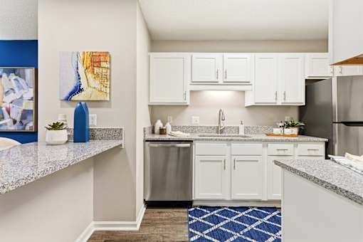 A kitchen with white cabinets and a blue rug.