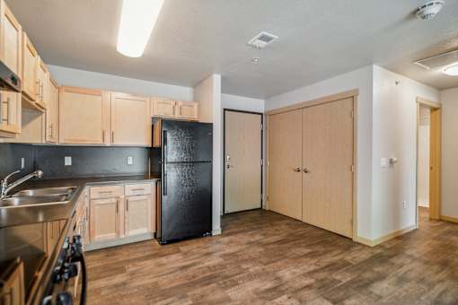 A kitchen with wooden cabinets and a black fridge.