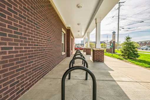 A long row of black bicycle racks are lined up on a sidewalk.