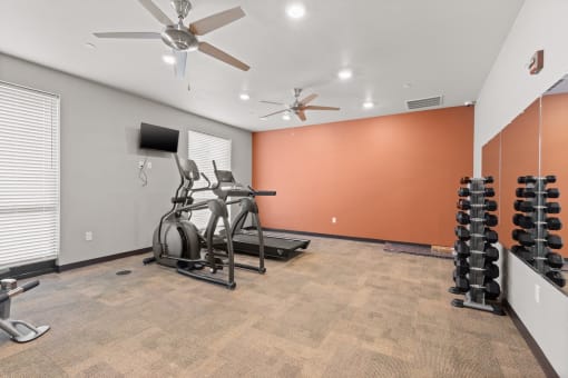 Fitness center with cardio equipment and free weights at River Flats Apartments