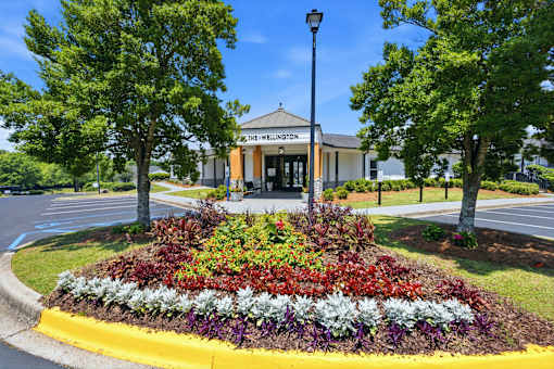 A flower bed in front of a building with the name "The Wellington" on it.