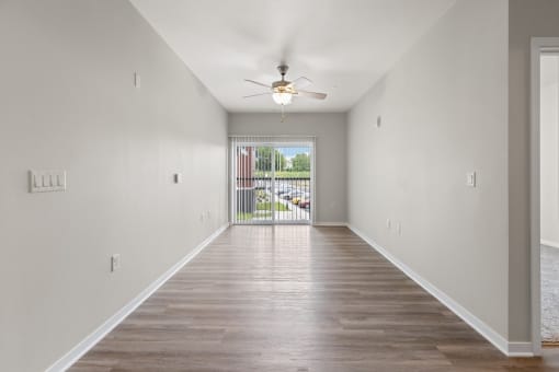 a large living room with wood-style flooring, a ceiling fan, and a large window