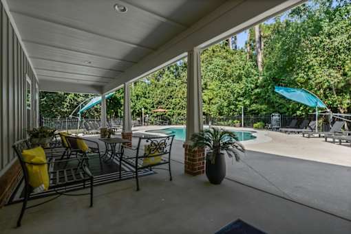 A patio with a table and chairs overlooking a pool.