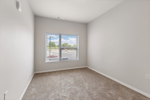 a bedroom with a large window filled with natural light in a home at River Flats Apartments