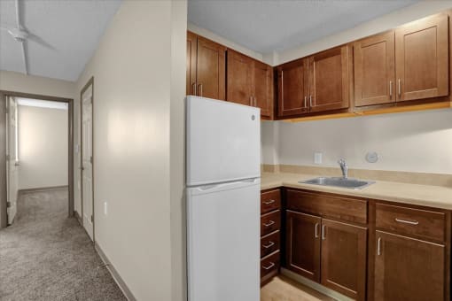 a kitchen with a white refrigerator and wooden cabinets
