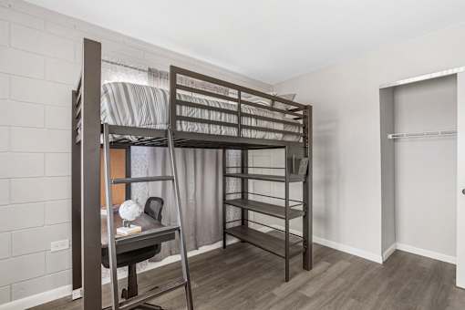 A room with a bunk bed and a desk.