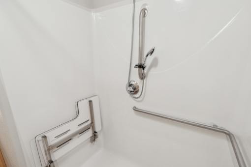 A white bathroom with a shower and a grab bar.