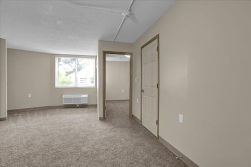 an empty living room with a white door and a window