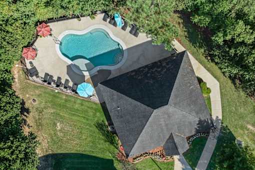 A backyard with a pool and a black tarp covering a structure.
