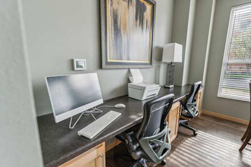 A modern home office with a large painting on the wall and a desk with a computer and printer.