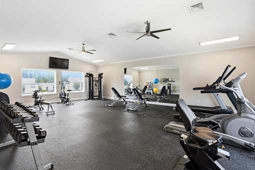 A spacious gym with a variety of equipment including treadmills, stationary bikes, and weight machines.