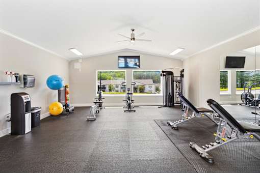 A spacious gym with a variety of equipment including a treadmill, exercise ball, and weight machines.