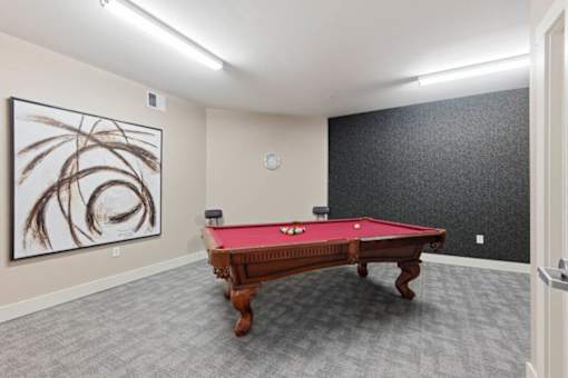 A pool table in a room with a painting on the wall.at The Lodge at Johns Road Apartments, Huntsville, AL, 35806