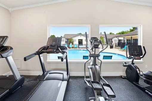 A room with a treadmill, elliptical trainer and a stationary bike.