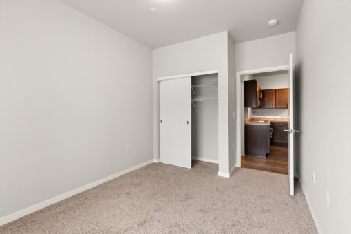 a bedroom with a sliding door closet and a door that opens into the kitchen