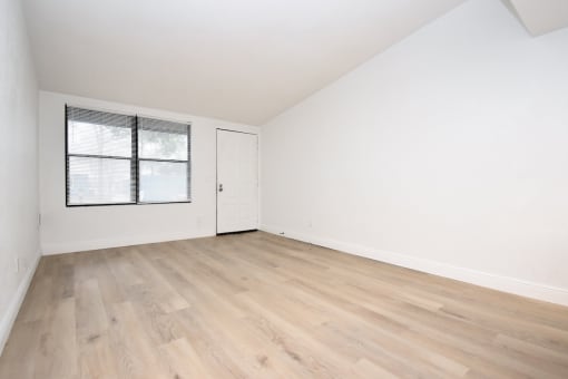 an empty living room with white walls and wood-style floors