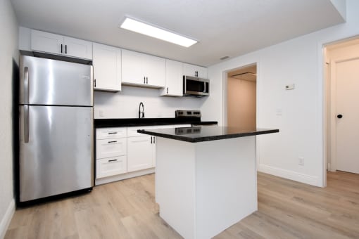 a kitchen with white cabinets and a stainless steel refrigerator