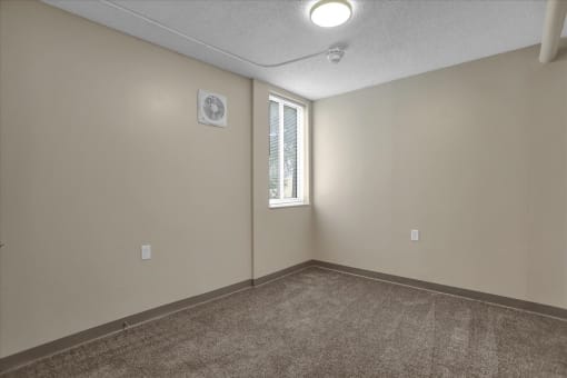 an empty living room with a window and carpet