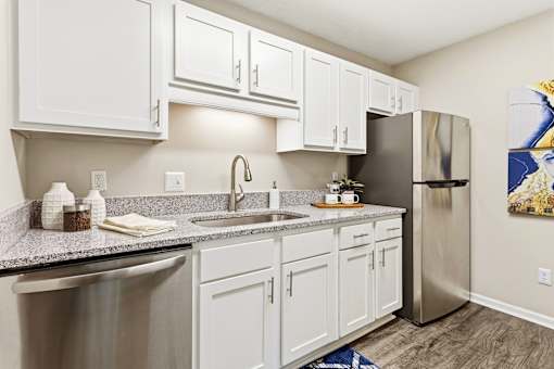 A kitchen with white cabinets and a stainless steel refrigerator.