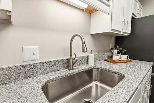 A kitchen with a granite countertop and a stainless steel sink.