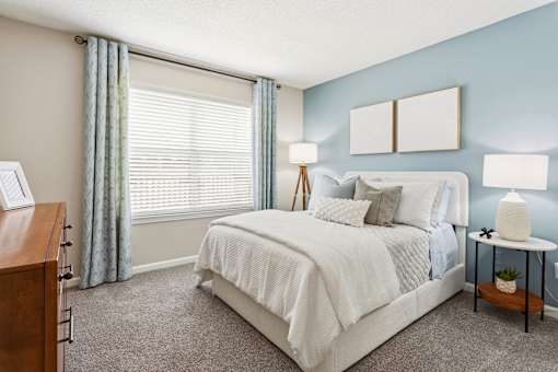 A bedroom with a bed, nightstands, and a window with blinds.