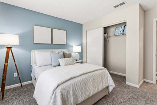 A bedroom with a bed, nightstands, and a closet.