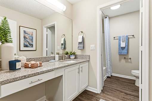 A bathroom with a white counter top and a white sink.
