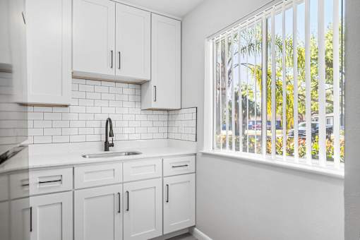 A kitchen with white cabinets and a white sink.