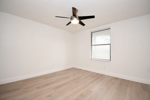 an empty living room with a ceiling fan and a window