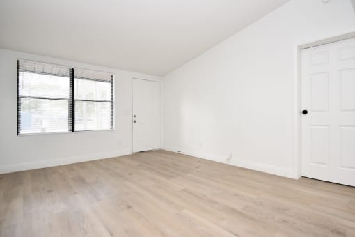 apartment living room with front door, large window, and wood-style flooring