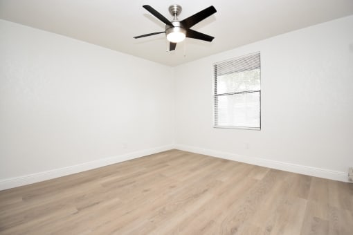 an empty room with white walls and a ceiling fan