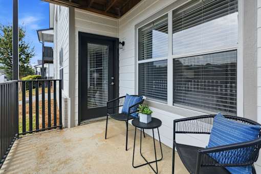 A black chair with a blue cushion is on a patio.