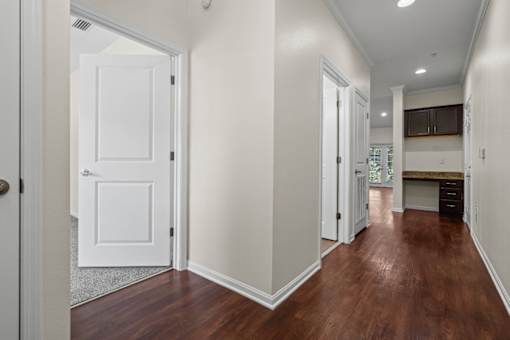 A hallway with a white door and brown flooring.