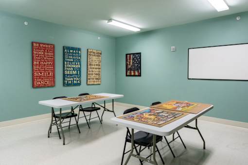A room with tables and chairs and a whiteboard on the wall.