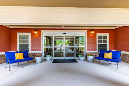 A red building with a glass door and two blue couches in front.