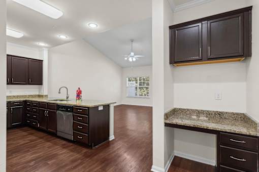 A kitchen with dark brown cabinets and a granite countertop.