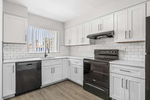 A kitchen with white cabinets and black appliances.