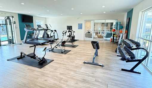 A gym with treadmills, exercise bikes, and weights.