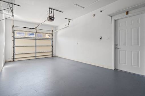 A white door is on the right side of a room with a grey floor.
