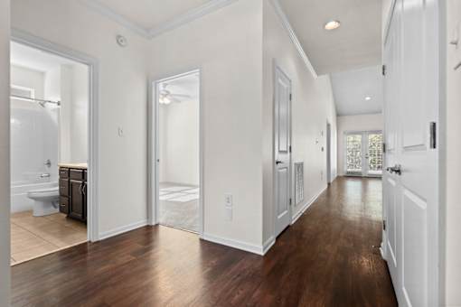 A long hallway with white walls and wood floors.