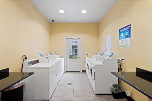 laundry center with washers, dryers, and folding tables at Fenwyck Manor