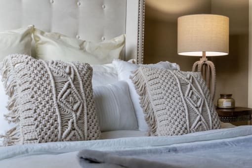 a bed with knit pillows and a plush headboard