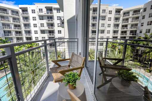 A balcony with two chairs and a table with a potted plant on it.