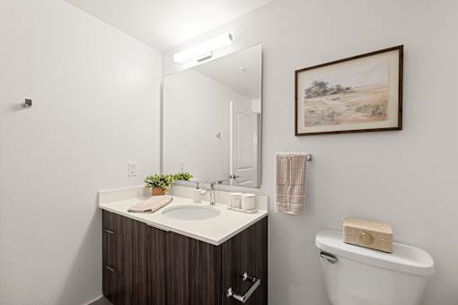 A bathroom with a brown vanity and a white toilet.