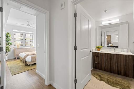 A bathroom with a white door and a mirror above the sink.