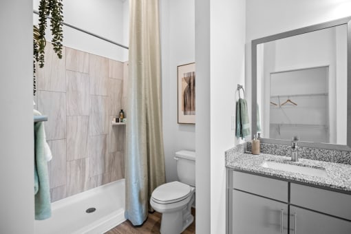 a bathroom with a toilet sink and shower and a mirror